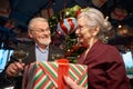 Elder y woman giving present to man on New Year clinking glasses of champagne Royalty Free Stock Photo