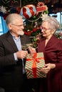 Elder man giving present to woman on New Year clinking glasses of champagne Royalty Free Stock Photo