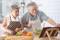 Elder couple read cookbook cooking in kitchen Royalty Free Stock Photo