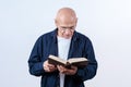 Elder hairless man wearing eyeglasses holding and reading book Royalty Free Stock Photo