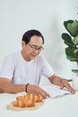 Elder man drinking milk and reading book while having breakfast Royalty Free Stock Photo