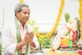 Elder man offering Bhajan or hymn in front of Lord Ganesha Idol during Ganesha or vinayaka Chaturthi festvial ceremony