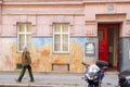 Elder man is passing by a pastel colorful painted building in Vienna, Austria