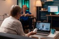 Elder patient with bottle of pills in hand using video call