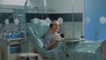 Elder patient using laptop and headphones in hospital ward Royalty Free Stock Photo