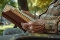 An elder\'s wrinkled hands tenderly hold an open book.