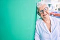 Elder senior woman with grey hair smiling happy leaning on the wall outdoors Royalty Free Stock Photo