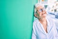 Elder senior woman with grey hair smiling happy leaning on the wall outdoors Royalty Free Stock Photo