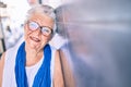 Elder senior woman with grey hair smiling happy leaning on the wall outdoors Royalty Free Stock Photo