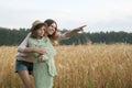 Elder sister hugged younger and shows a hand to the side