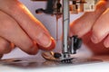 Elder woman fingers inserting a red thread into a sewing machine`s needle, close-up Royalty Free Stock Photo