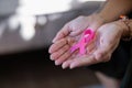 Elder woman hand holding pink ribbon symbol. Breast cancer awareness and october pink day, world cancer day, national