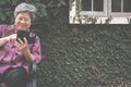 elder woman holding mobile phone in garden. elderly female texting message, using app with smartphone in park. senior use
