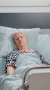 Elder woman with IV drip bag sleeping in hospital ward bed Royalty Free Stock Photo