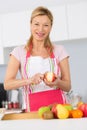 Elder woman peeling apples in kitchen Royalty Free Stock Photo