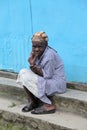 Elder woman sits on steps of village building