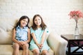 Elder and younger sisters posing together on the couch at the ca