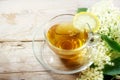 Elderflower tea with lemon and some blossoms on a rustic wooden table, natural home remedy for blood cleansing and against cold