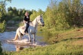 An elderly active woman goes to the shore of the pond on a white horse Royalty Free Stock Photo