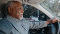 Elderly african american businessman driving automobile on roadway experienced confident driver carefully looks at road