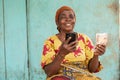 an elderly african woman holding phone and money Royalty Free Stock Photo