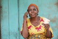 an elderly african woman holding some money, making phone call Royalty Free Stock Photo