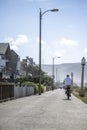 An elderly man rides a bicycle on a footpath along the Pacific coast, preferring an active healthy lifestyle