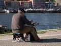 Elderly artist painting by River Douro in Porto, Portugal on a summer day.