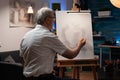 Elderly artist working on vase drawing with pencil on canvas