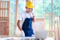 Elderly Asian carpenter with mustache wearing antiknock helmet and cloth gloves, talking on mobile phone with customer, senior Royalty Free Stock Photo