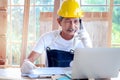 Elderly Asian carpenter with mustache wearing antiknock helmet and cloth gloves, talking on mobile phone with customer, senior Royalty Free Stock Photo