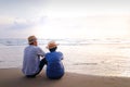 An elderly Asian couple sitting on the beach Look at the beautiful sea in the morning together. Royalty Free Stock Photo