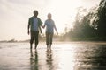 Elderly Asian couple walking on the beach at sunset