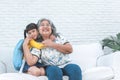 elderly Asian grandmother and her granddaughter is 6-year-old sitting on white sofa, are hugging, smile and happy together Royalty Free Stock Photo