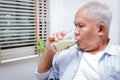 Elderly Asian man drink milk containing calcium to prevent osteoporosis.