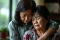 Elderly Asian Mother Provides Support And Comfort To Stressed Adult Daughter At Home