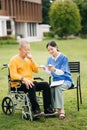 Elderly asian senior man on wheelchair with Asian careful caregiver and encourage patient, walking in garden. with care from a Royalty Free Stock Photo