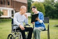 Elderly asian senior man on wheelchair with Asian careful caregiver. Nursing home hospital garden concept Royalty Free Stock Photo