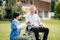 Elderly asian senior man on wheelchair with Asian careful caregiver. Nursing home hospital garden concept are walking in the Royalty Free Stock Photo