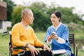 Elderly asian senior man on wheelchair with Asian careful caregiver. Nursing home hospital garden concept are walking in the Royalty Free Stock Photo