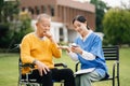 Elderly asian senior man on wheelchair with Asian careful caregiver. Nursing home hospital garden concept are walking in the Royalty Free Stock Photo