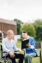 Elderly asian senior man on wheelchair with Asian careful caregiver and encourage patient, walking in garden. with care from a Royalty Free Stock Photo