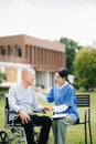 Elderly asian senior man on wheelchair with Asian careful caregiver and encourage patient, walking in garden. with care from a Royalty Free Stock Photo