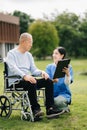 Elderly asian senior man on wheelchair with Asian careful caregiver. Nursing home hospital garden concept