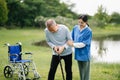 Elderly asian senior man on wheelchair with Asian careful caregiver. Nursing home hospital garden concept Royalty Free Stock Photo