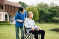 Elderly asian senior man on wheelchair with Asian careful caregiver. Nursing home hospital garden concept are walking in the Royalty Free Stock Photo
