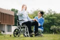 Elderly asian senior man on wheelchair with Asian careful caregiver. Nursing home hospital garden concept are walking in the Royalty Free Stock Photo