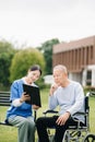 Elderly asian senior man on wheelchair with Asian careful caregiver. Nursing home hospital garden concept are walking in the Royalty Free Stock Photo