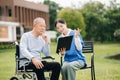 Elderly asian senior man on wheelchair with Asian careful caregiver. Nursing home hospital garden concept are walking in the Royalty Free Stock Photo