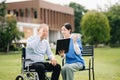 Elderly asian senior man on wheelchair with Asian careful caregiver. Nursing home hospital garden concept are walking in the Royalty Free Stock Photo